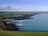 Extensive view of the Anglesey coastline and bay with a calm blue ocean, rocky cliffs and green plateau, Wales, UK