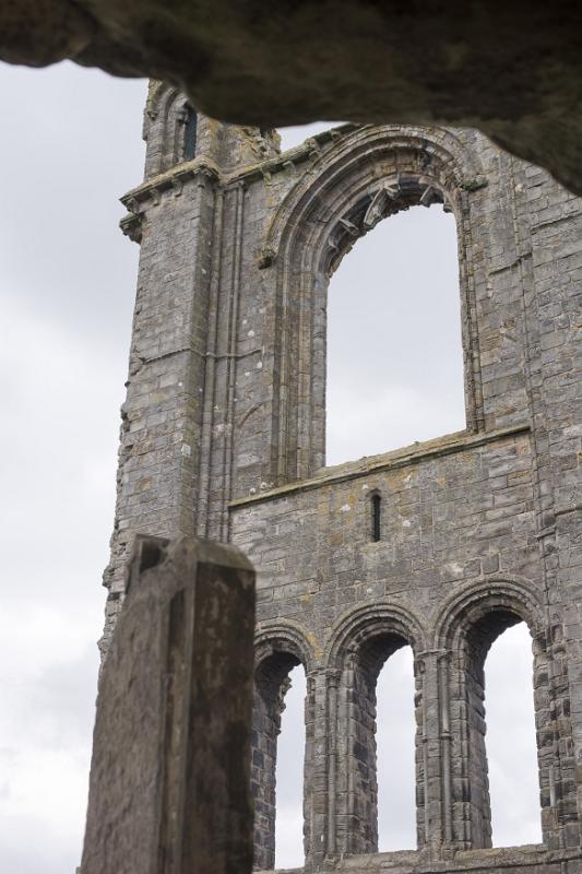 Detail of the St Andrews Cathedral ruins, Scotland showing the arched gothic windows in an ancient stone wall with view through to a hazy sky