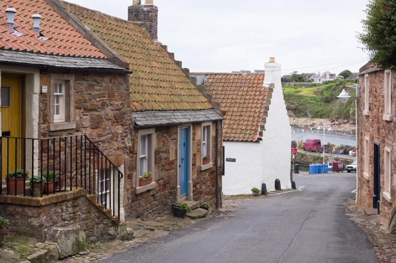 Old stone cottages, Crail, Fife coast, Scotland on a deserted narrow lane leading down to the water and parked cars