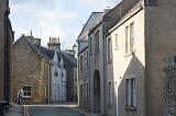 Two people walking through a narrow back street past historic cottages and townhouses, St Andrews, Scotland