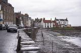 Puddles of water on street, near apartments and automobiles under cloudy skies in Cellardyke, Scotland