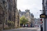 Street view in the historic town of St Andrews, Scotland showing the old stone architecture, church and businesses