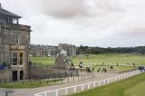View of white fences and various golfers playing on golf green under overcast sky in Saint Andrews, Scotland