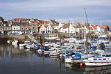 Scenic view of boats moored in Anstruther harbour, Scotland with an assortment of fishing boats, motorboats, sailboats and yachts overlooked by waterfront houses