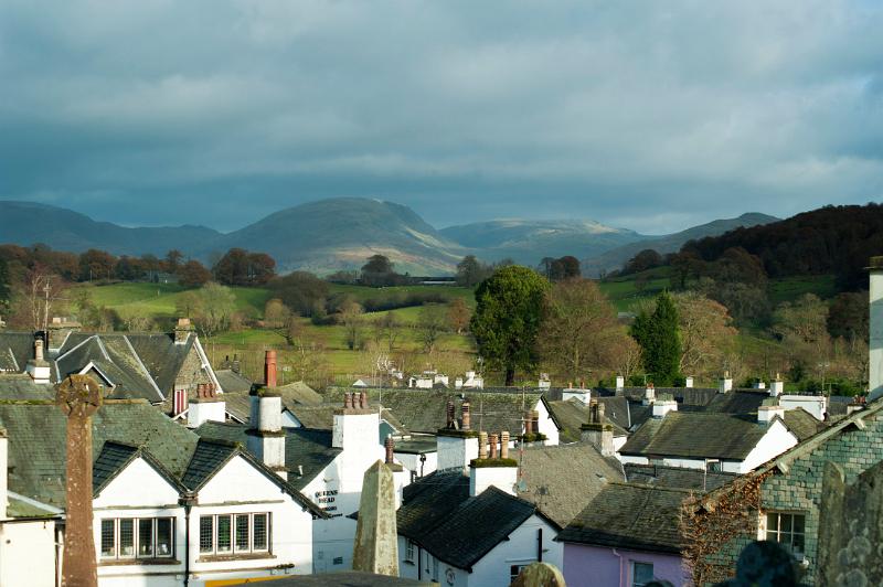 View over the rooftops of Hawkshead village towards lush green countryside and Wansfell Pike in the Lake District