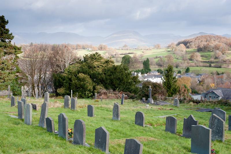 Gravestones in the churchyard at Hawkshead in the English Lake District with a view to beautiful lush green countryside and hills beyond