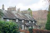 Row of quaint Cumbrian stone cottages at Skelwith Bridge with cylindrical stone chimney pots and neat front gardens
