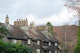 Row of quaint stone cottages at Skelwith Bridge in the Lake District with traditional cylindrical chimney pots made of stone in a leafy green lane