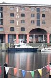 Row of little flags in foreground on view of boat docked at the Liverpool Albert Dock in the United Kingdom