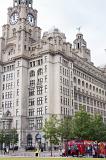 Liverpool Liver Building, a famous landmark in the city and part of the UNESCO designated World Heritage Maritime Mercantile City, with a traditional red tourist bus in the foreground with tourists