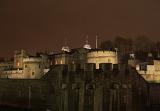 Night view of the iconic landmark Gothic structure of the Tower of London illuminated by lights showing the detail of the round towers