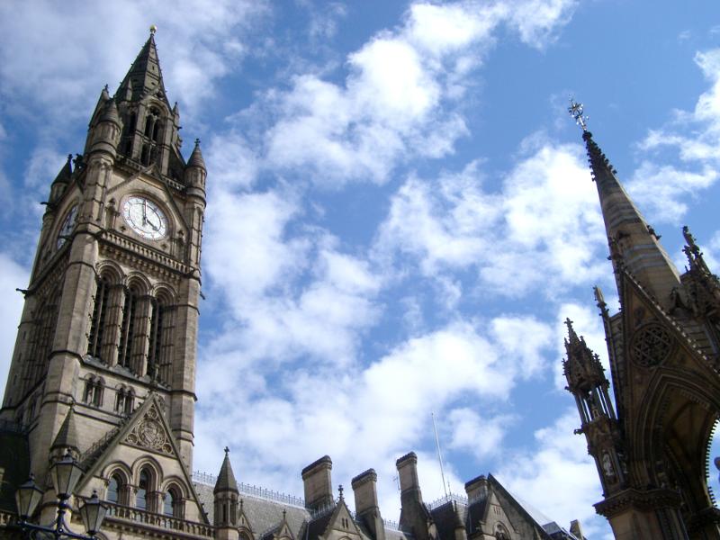Gothic revival clock tower on the Manchester Town Hall against a cloudy blue sky