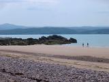 Sandy beach on the shores of Lock Gairloch in the Scottish highlands with people walking along the waters edge in the sunshine