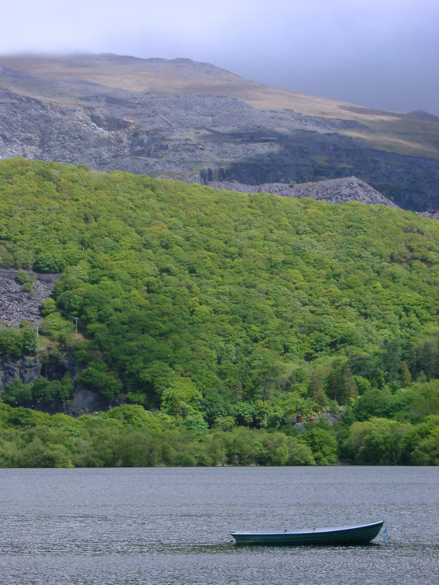 an image of Small boat on Llyn Padam lake near Llanberis in Gwynedd, North Wales with rugged mountains on a misty day
