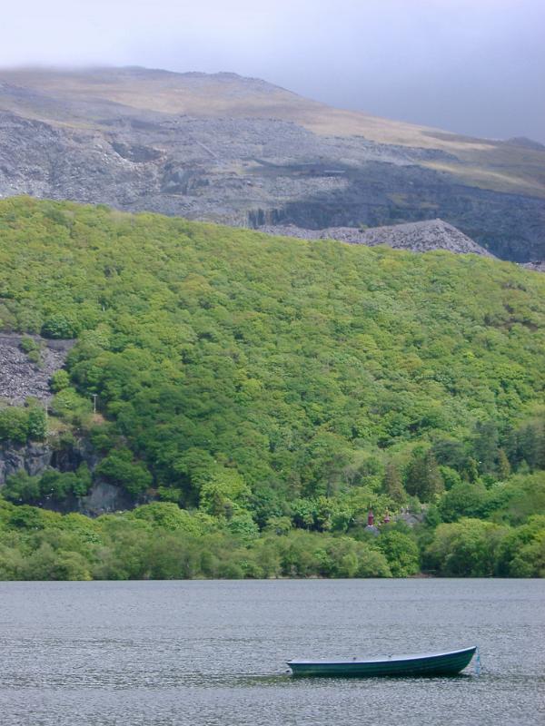 Small boat on Llyn Padam lake, Llanberis Small boat on Llyn Padam lake near Llanberis in Gwynedd, North Wales with rugged mountains on a misty day