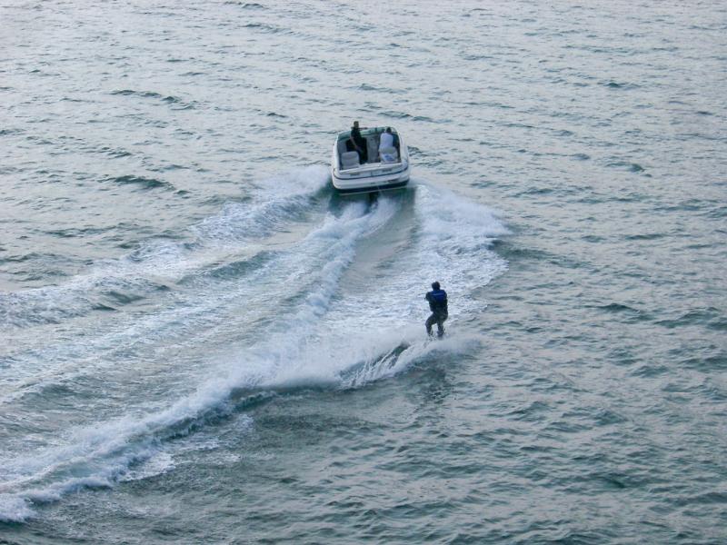 Speedboat and skier in a wetsuit High angle view of a speedboat and skier in a wetsuit speeding away from the camera in a depiction of extreme sport and outdoor activity