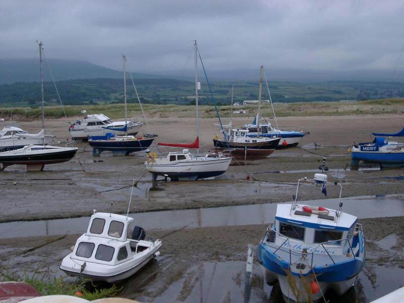 Small fishing boats beached on mud flats in an estuary stranded on the sand by the receding tide on Shell Island