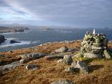 Stone cairn on a coastal headland lookout overlooking the coastline of the Hebrides, Scotland on a stormy day