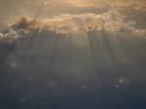 Suns rays shining through a gap in the clouds in a background cloudscape image of nature and the environment