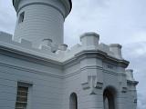 Close up Vintage White Byron Bay Lighthouse Structure on Lighter Blue Gray Sky Background.
