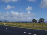 Beautiful Spot at Wide Grassy Grampians Field Along the Road on Lighter Blue and White Sky Background.