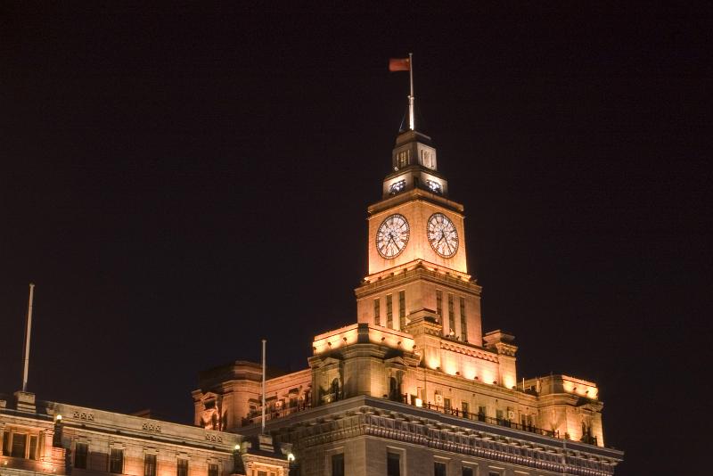 Customs House, or the Bund, Shangai, China illuminated at night with a flag flying at full mast above