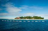 View across ocean of a line of jet skis moored in front of Beachcomber Island, Fiji with its small resort