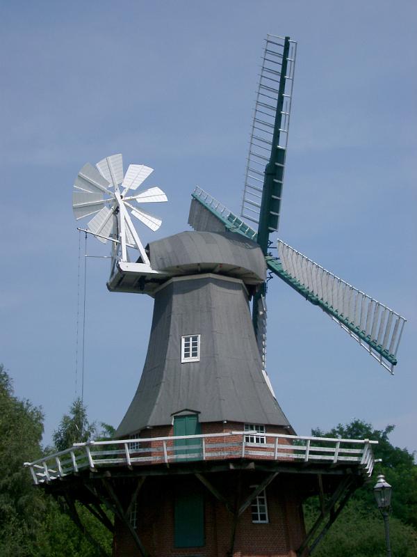 Historic windmill in Berlin with large wooden sails for converting kinetic energy from the wind and a secondary smaller windmill mounted on its side