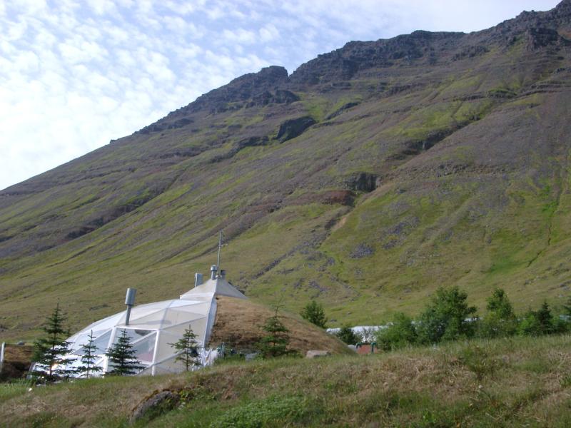 Environmentally friendly biodome, or dome house in Isafjordur in Iceland partially covered in turf built at the foot of a volcanic mountain
