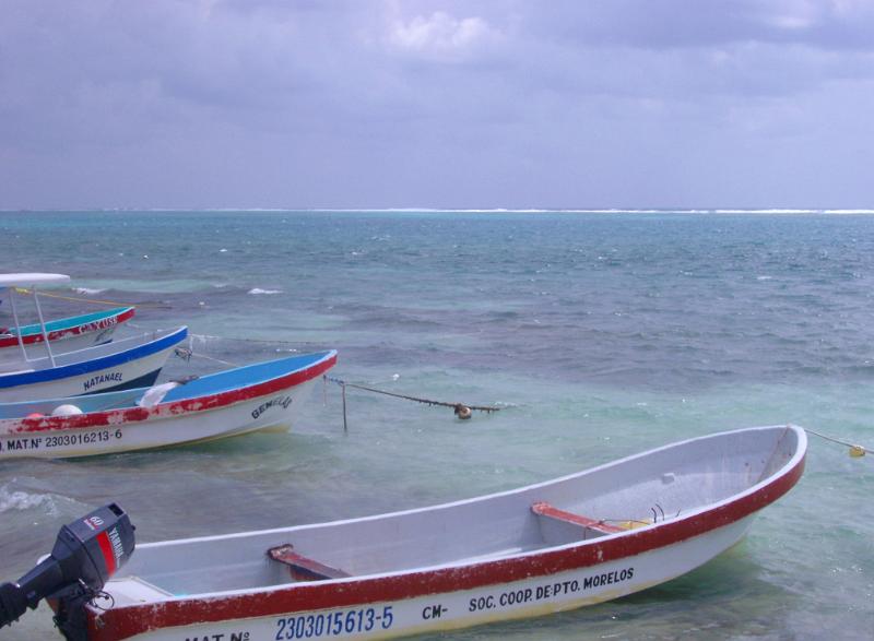 Line of small motorboats with outboard motors moored in a line along the shore pointing out to sea at a Mexican port