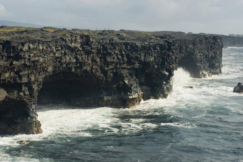 Rugged oceanscape with vertical rocky cliffs above a stormy sea on Big Island, Hawaii