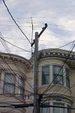 San Francisco architecture with a view of the historical wooden facades of townhouses past a spaghetti junction electricity pole