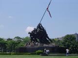 Historic Black War Memorial Statue of Marine Corps with American Flag on Huge Platform. Isolated on Light Blue Gray Sky Background.