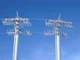 Detail of an alpine chair lift showing the towers and cables with the pulleys against a clear blue sunny winter sky