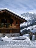 Scenic view of the front facade of a typical wooden alpine lodge in a village in snow covered mountainous terrain