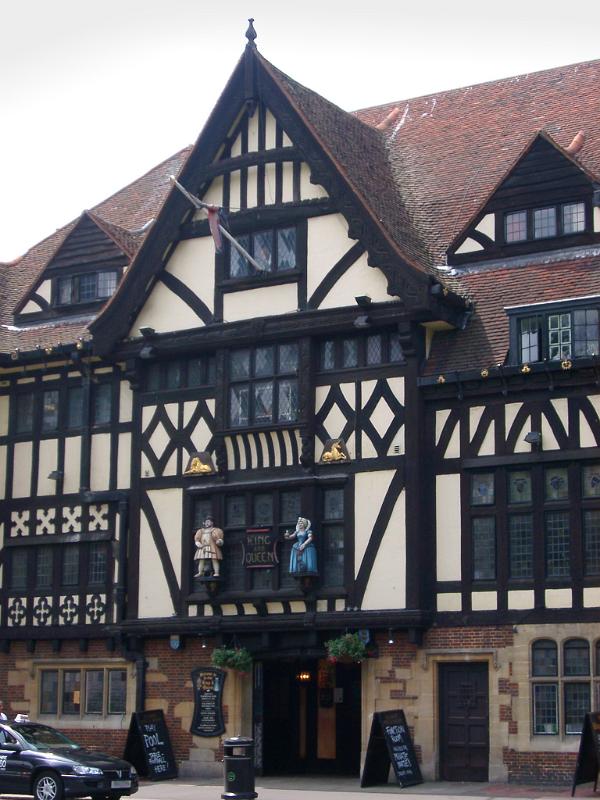 Tudor frame pub facade showing the traditional exterior timber framework on the white walls with two statues above the entrance and menus displayed in the street