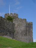 Historic Conwy Tower on Grassy Landscape in Conwy, North Coast of Wales on a Light Blue Sky Background.