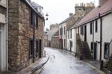 Narrow street in Cellardyke, Scotland lined with quaint cottages on a rainy overcast day