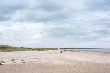 Wide open sandy beach with trails of footprints under cloudy sky at Saint Andrews, Scotland