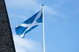 Scottish flag flying in St Andrews, Scotland fluttering in the wind on a white flagpole against a hazy blue sky