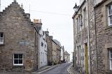 Two rows of old stone brick residential buildings on narrow road in Scotland near Saint Andrews