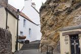 Cut rock with doorway and staircase with traditional Scottish houses in Pittenweem Scotland, the entry way to access st fillan's cave.