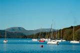 Yachts moored to buoys on the calm water of the lake at Windermere in the Lake District in Cumbria
