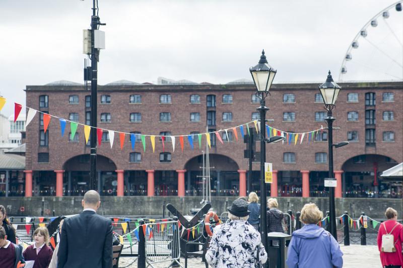 Tourists at Liverpool Albert Dock People in cool weather clothing gathering near Liverpool Albert Dock outside under old fashioned street lamps