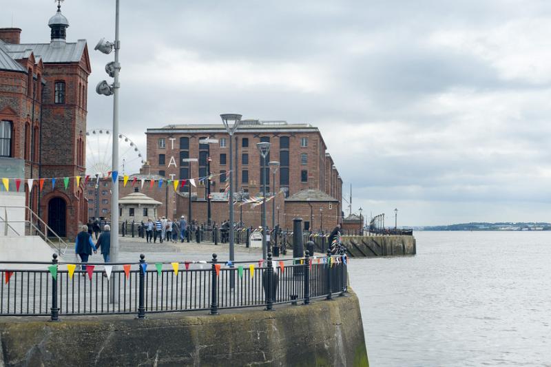railings along waterfront at Liverpool Mersey Various tourists walking around landmark buildings near round railing along waterfront at Liverpool Mersey