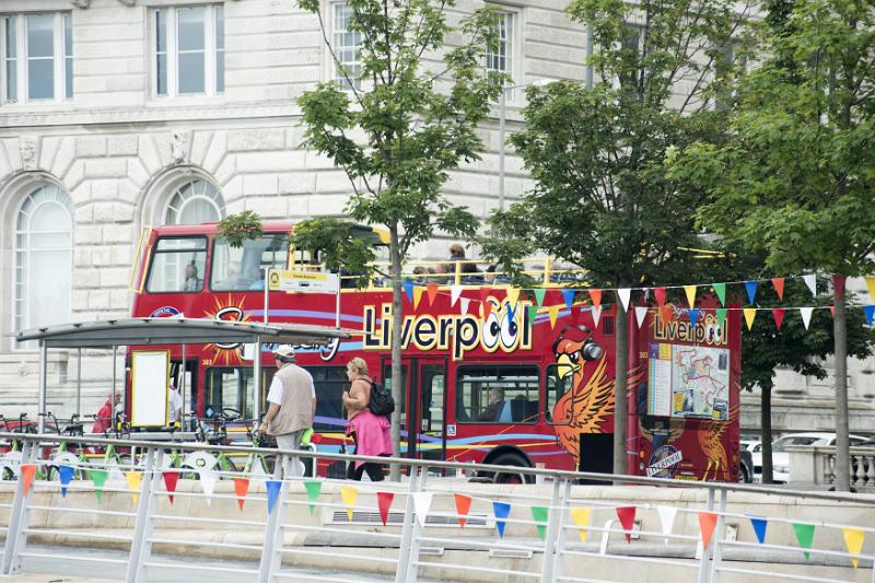 Traditional red double decker bus, Liverpool Traditional British red open top double decker tourist bus, Liverpool, England with colorful bunting and pedestrians
