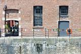 Brick wall with railings at foreground with windows and doors above stone wall with copy space at Liverpool Albert Dock