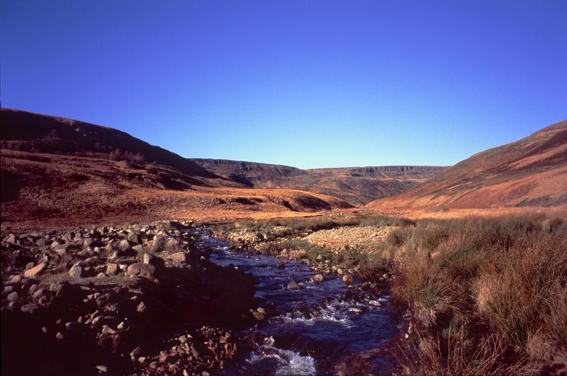 Meandering rocky stream in a wide open valley and moorland in the Pennines in North West England