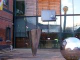 Entrance to the Manchester Museum for science and industry with on outdoor sculpture of a shiny metal silver sphere