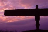Angel of the North sculpture at Gateshead, Newcastle, with its outstretched wings silhouetted against a purple sky at sunset